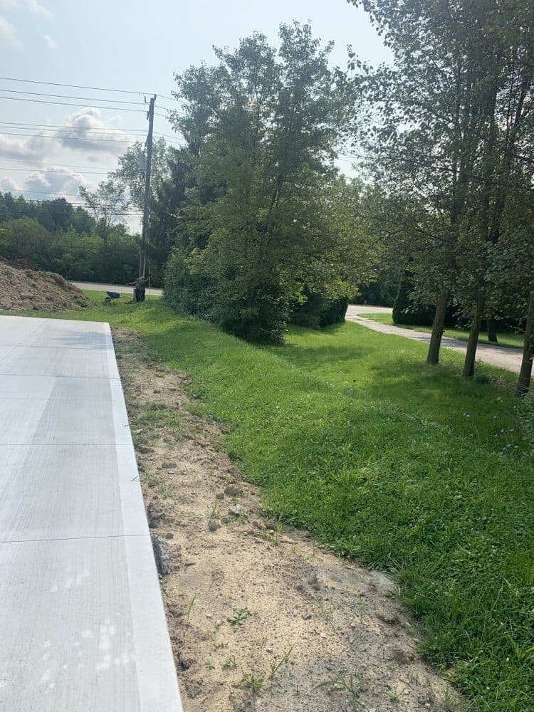 Fresh concrete driveway edge with the lawn being restored alongside